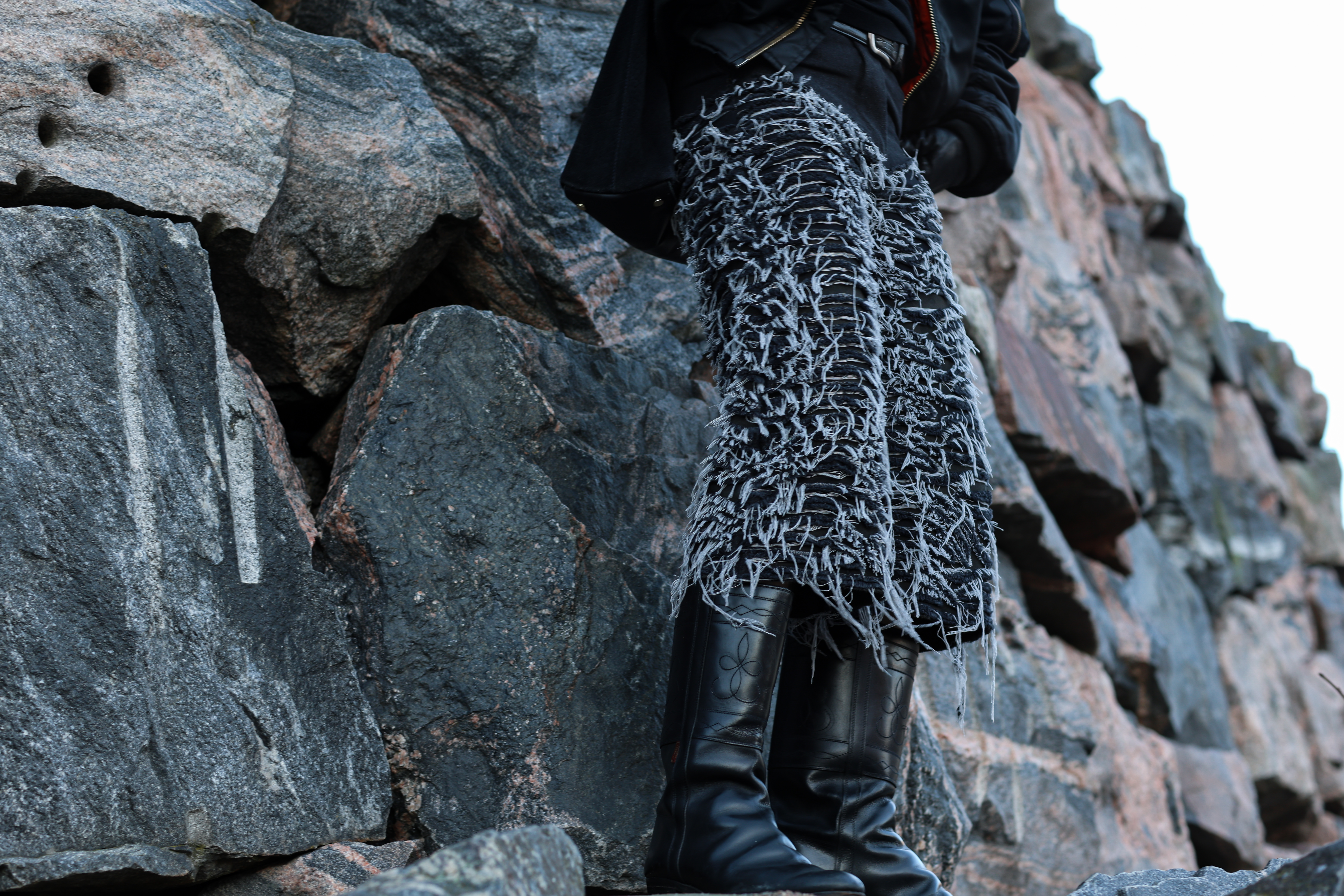 Detail of distressed Lorimer trousers and boots against rocks